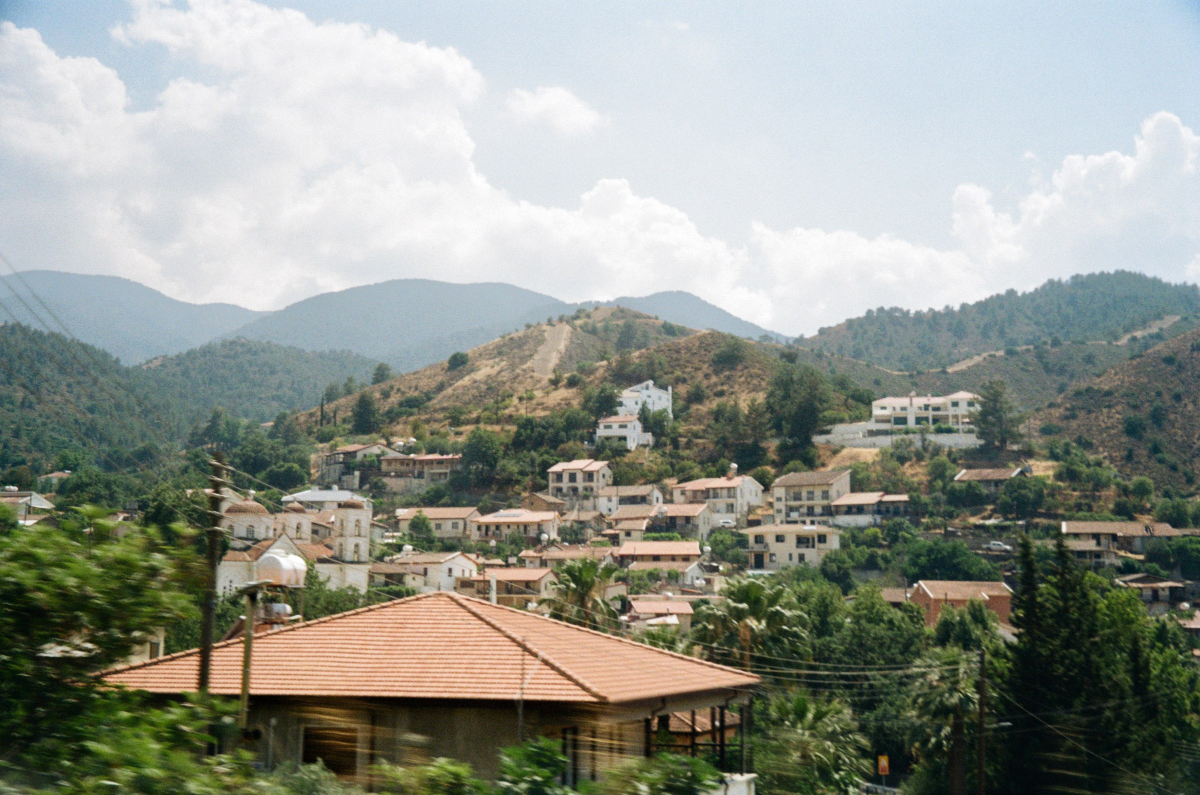 A hillside village with terracotta roofs under a cloudy sky