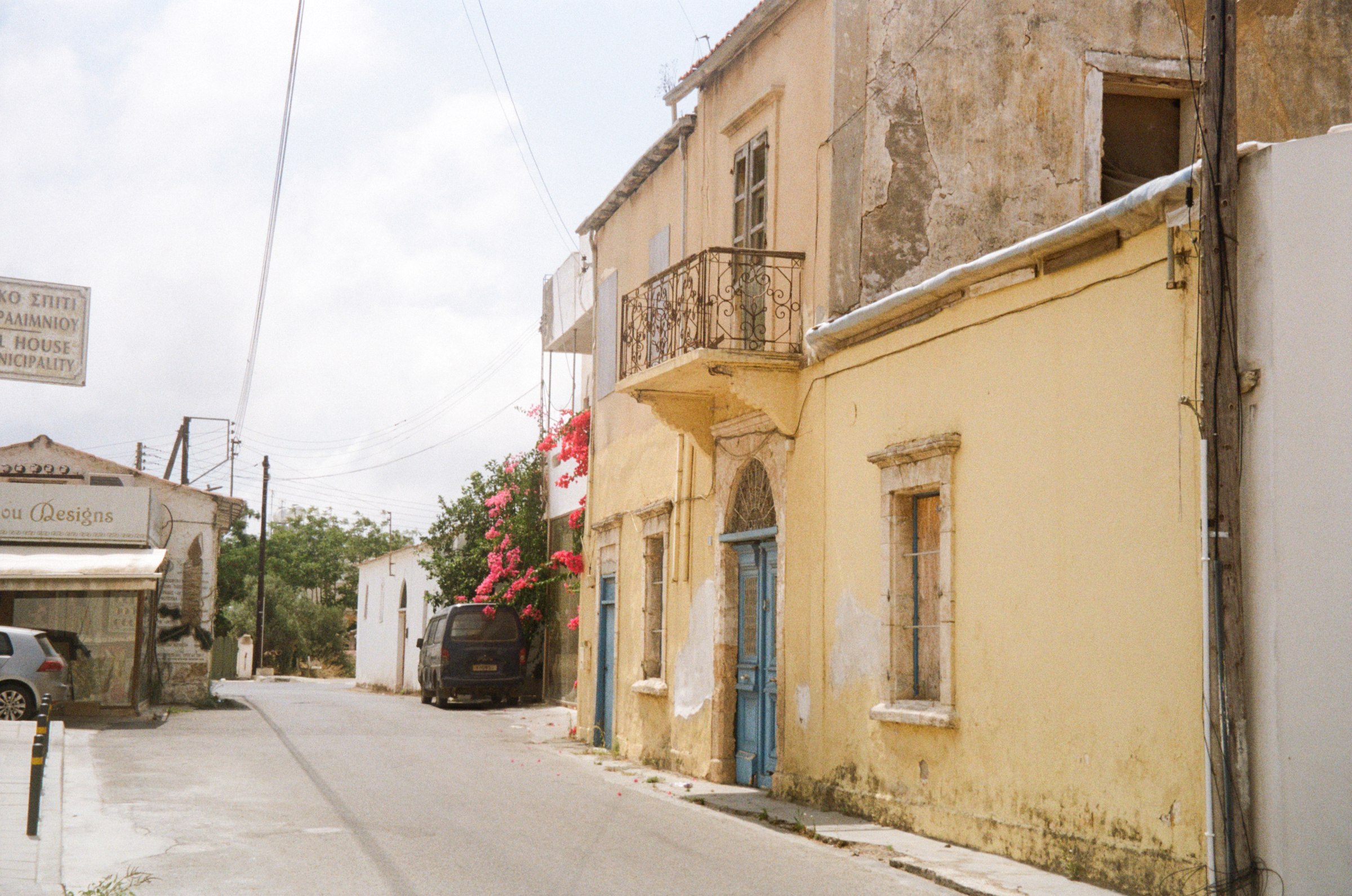 A weathered old-town street with a blue door and bougainvillea