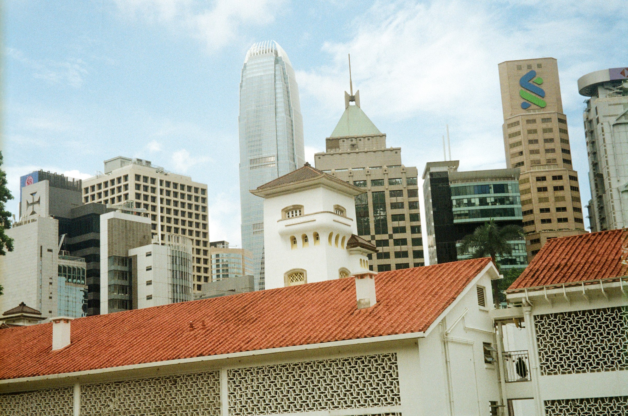 A red-tiled roof against the modern skyline behind