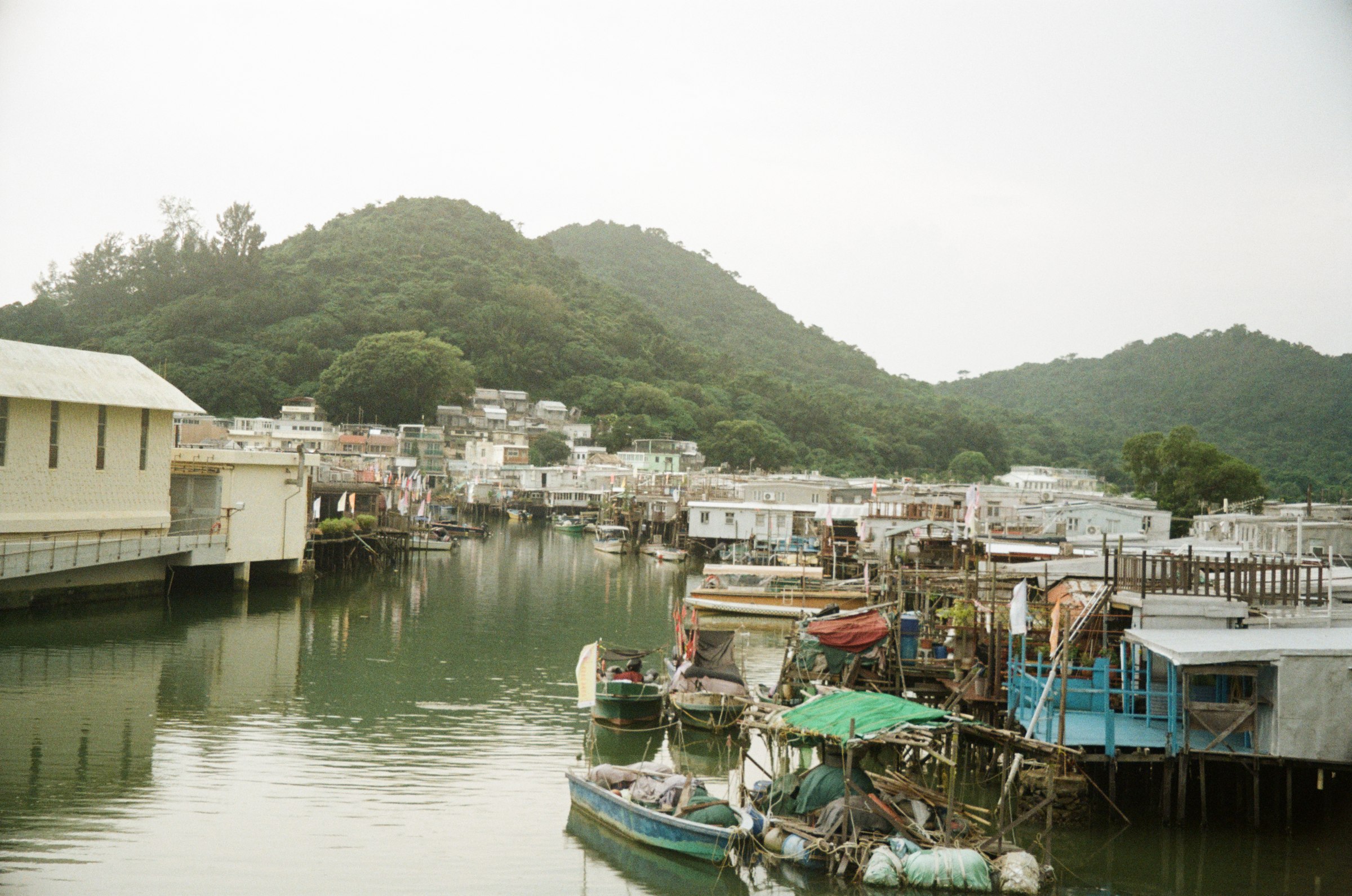 Tai O village canal with boats, hills behind