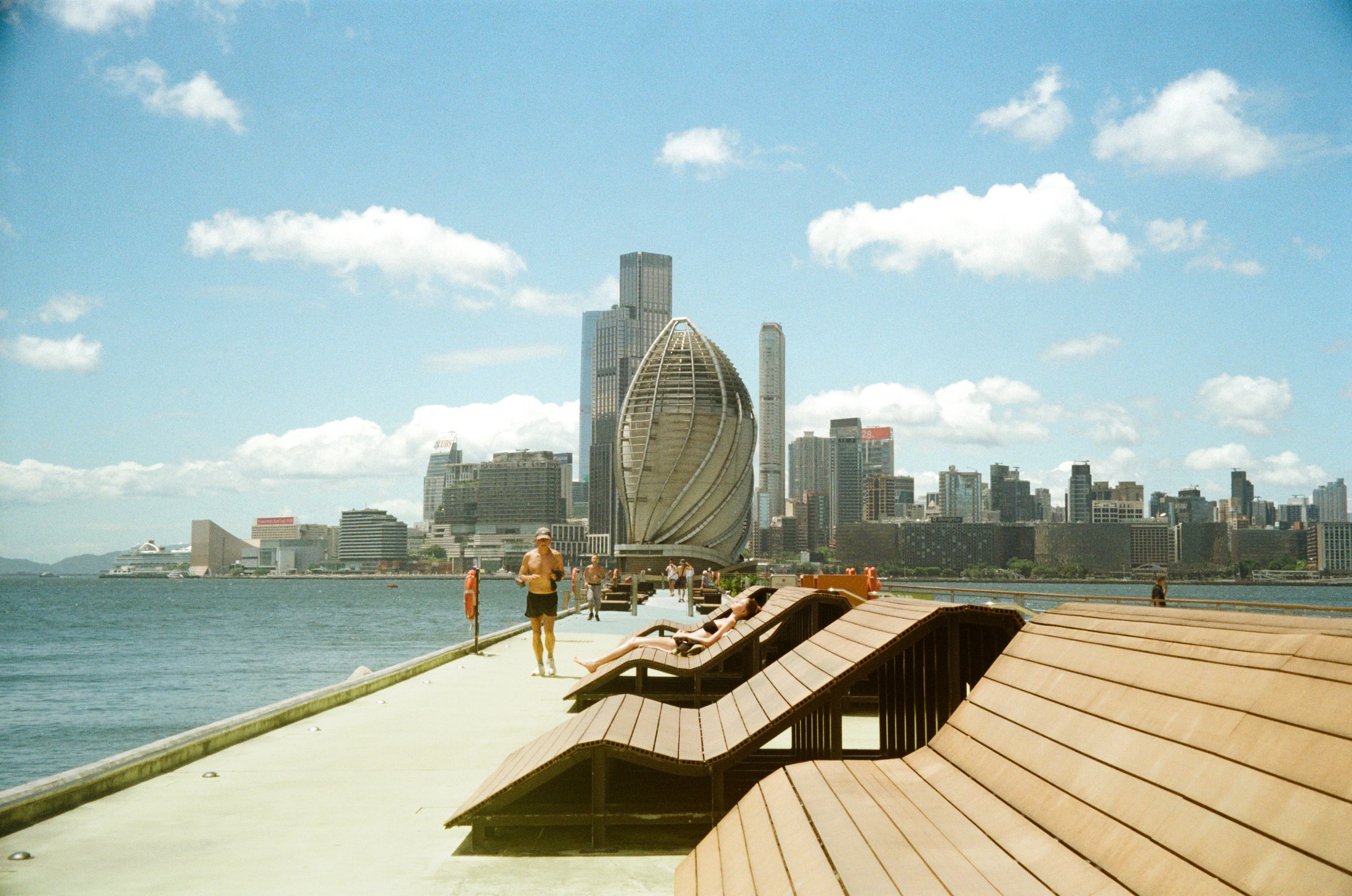Waterfront promenade loungers facing the Hong Kong skyline